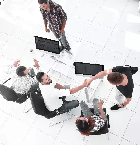 Στελέχη εταιρείας συνεργάζονται γύρο από ένα τραπέζι με υπολογιστές.